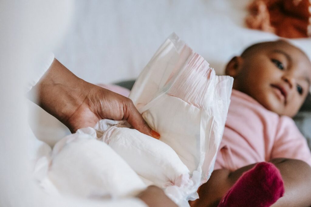 High angle of crop African American mom changing nappy for cute little baby lying on changing table